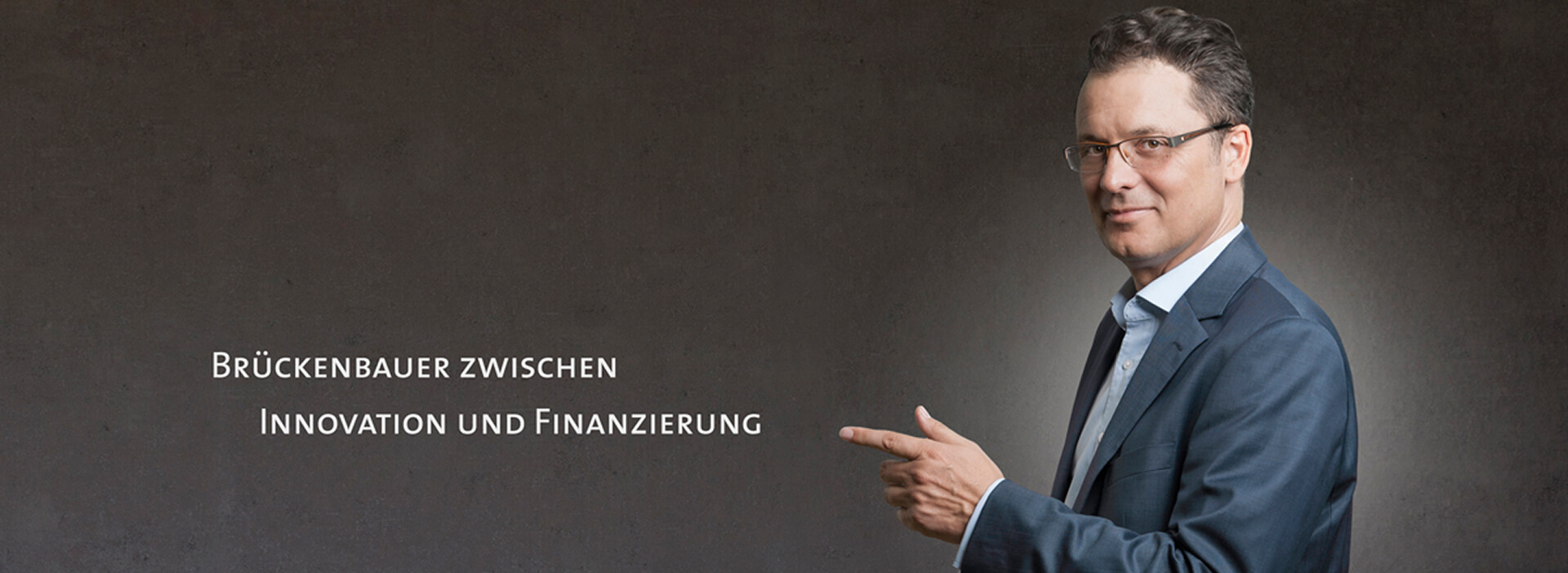 Geschäftsführer von FörderProTech zeigt in Richtung des Schriftzugs „Brückenbauer zwischen Innovation und Finanzierung